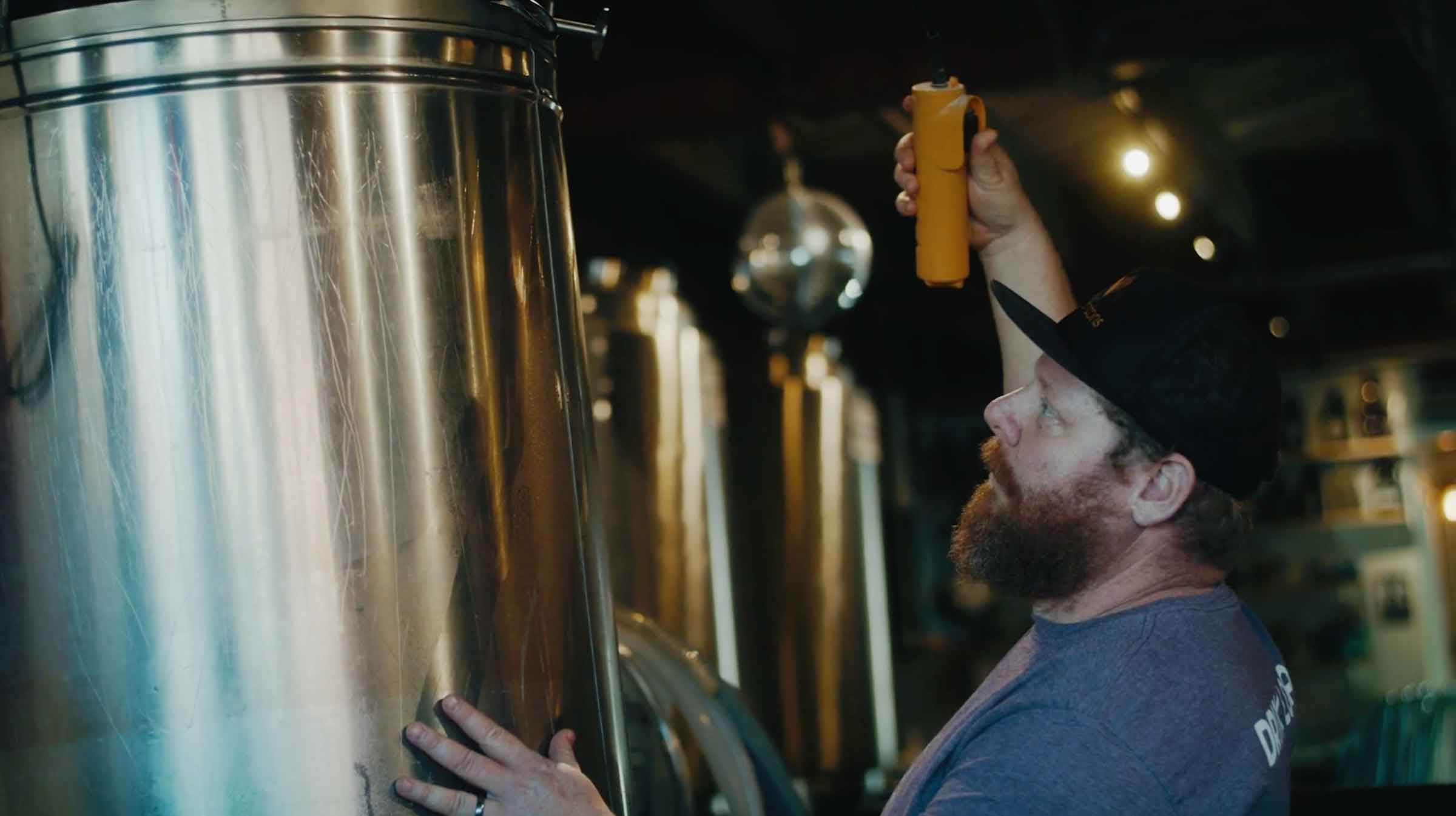 Jason Snyder checks brewery tank at MicaTown Brewing in Marion, NC, Mountain BizWorks.