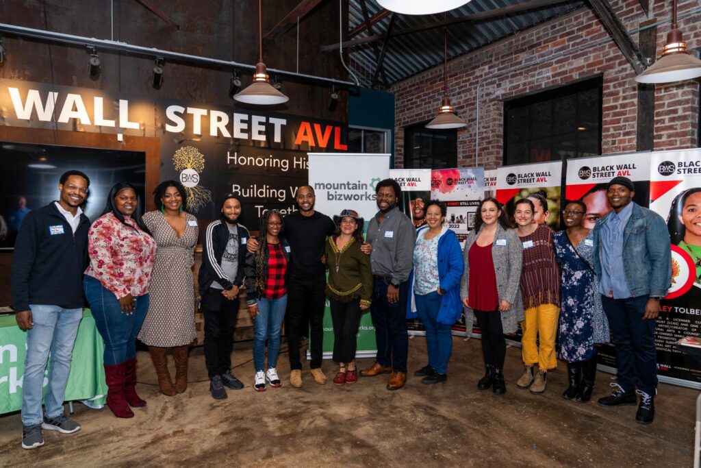 A group of eleven entrepreneurs of color and program leaders stand in a line, smiling.