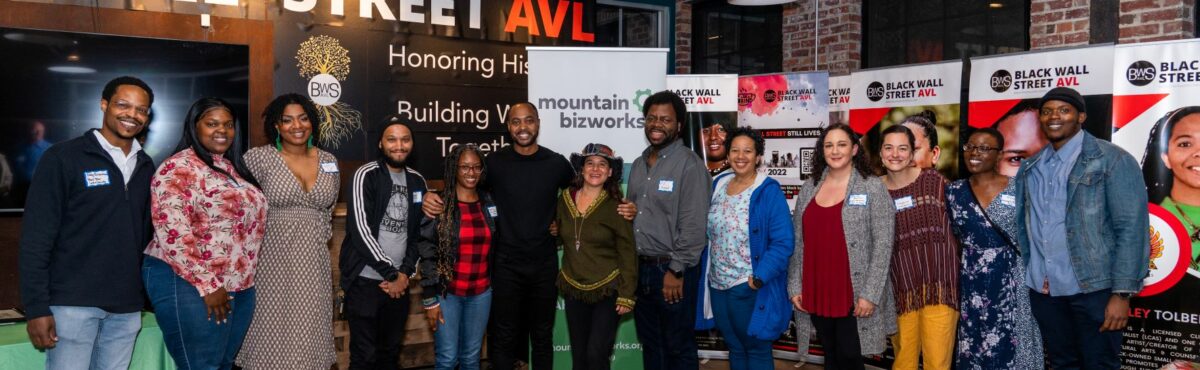 A group of eleven entrepreneurs of color and program leaders stand in a line, smiling.